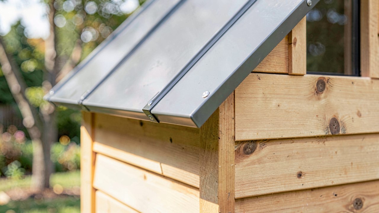 Close up of quality tiny house construction where cedar siding meets a standing seam metal roof with drip flashing